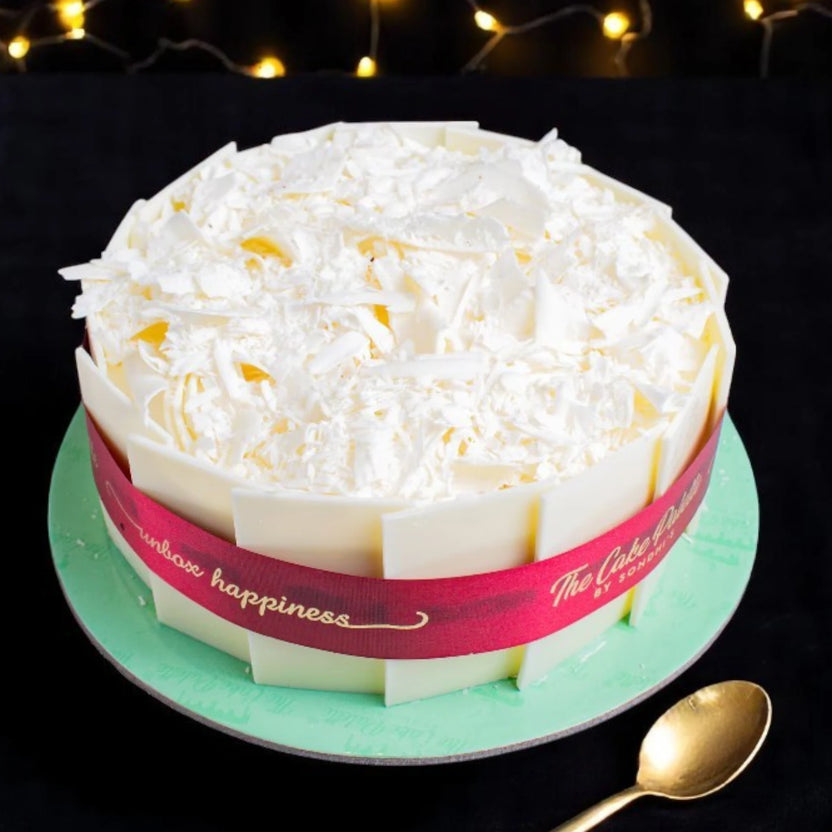 Snow Sweet Whiteforest Cake - White Chocolate Delight with white chocolate shards, vanilla sponge, and cherries, ideal for anniversaries and celebrations. Main image