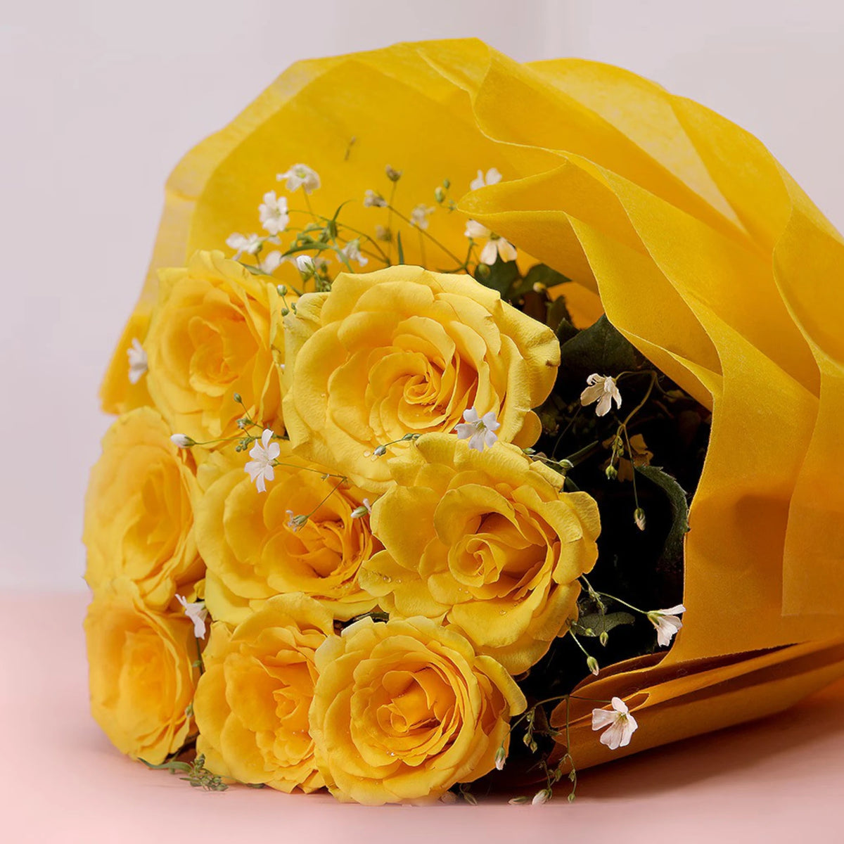 Close-up of 8 Yellow Roses bouquet with delicate white fillers, wrapped in yellow paper. Perfect for warm wishes or get-well-soon gifts.