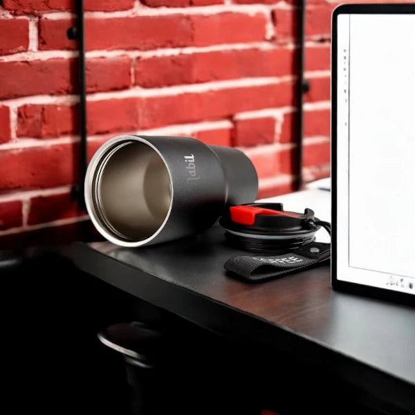 Personalized Not Your Habibi Sipper tumbler lying on its side near a laptop, showcasing stainless steel interior and detachable lid with red accent.
