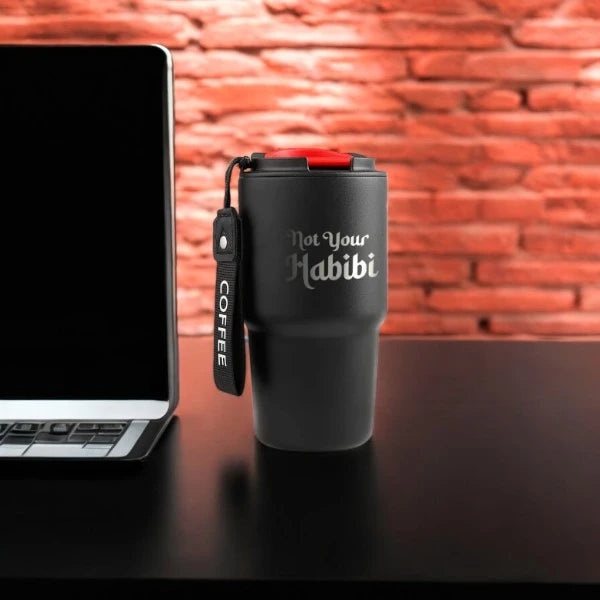 Not Your Habibi Sipper - Personalized Black tumbler standing upright beside a laptop, featuring a red-lid and 'COFFEE' strap for easy carrying.