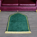 Green Dome Janamaz placed in front of a sofa, showcasing its dome shape and plush design for comfortable prayer sessions.