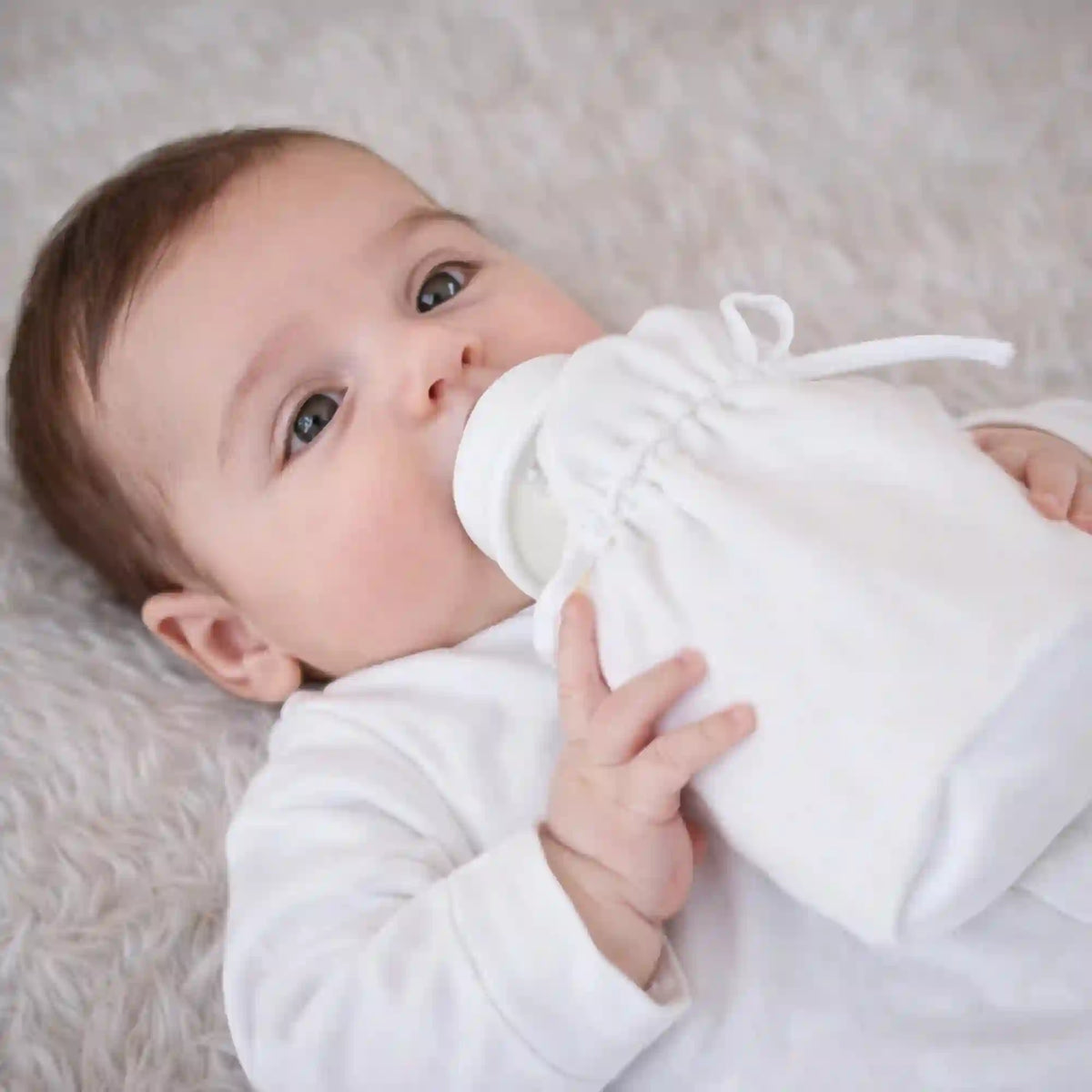 Personalized Newborn Baby Romper Set in white cotton, worn by baby lying on soft fur blanket. Ideal keepsake gift from Kids Collection.