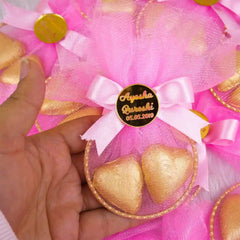 Close-up of pink Aqiqah Golden Hearts Favor held in hand, showcasing gold heart chocolates and personalized wedding tag.