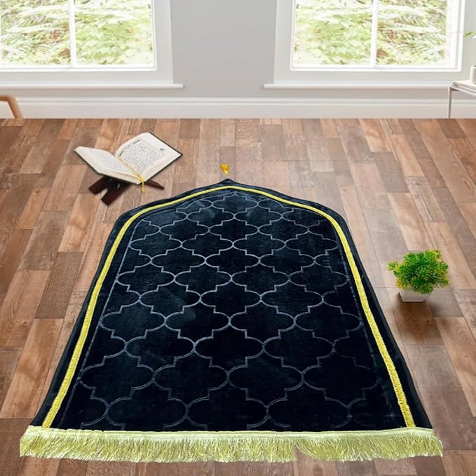 Black Dome Janamaz with golden border placed in a serene prayer setting with Quran and plant, enhancing spiritual ambiance.