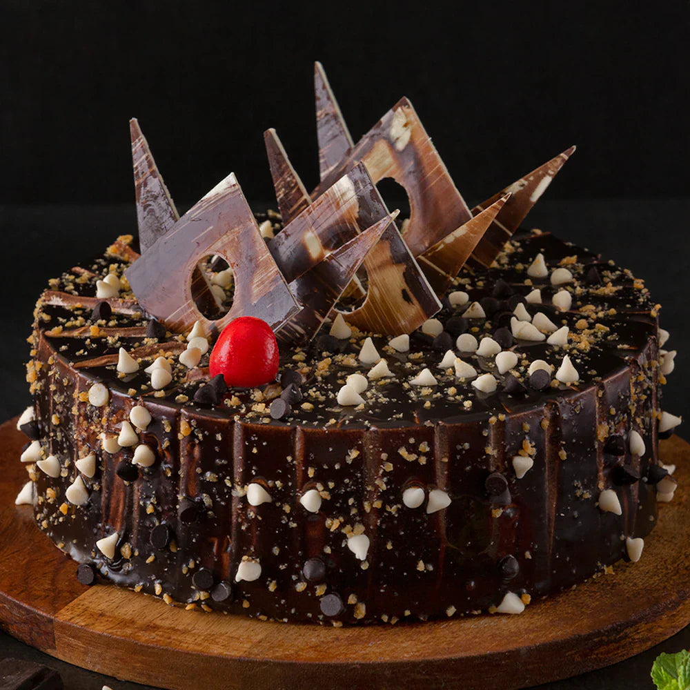 Round Marble Crunch Cake featuring chocolate vanilla swirls, crunchy toppings, and decorative chocolate shards for birthdays or anniversaries.