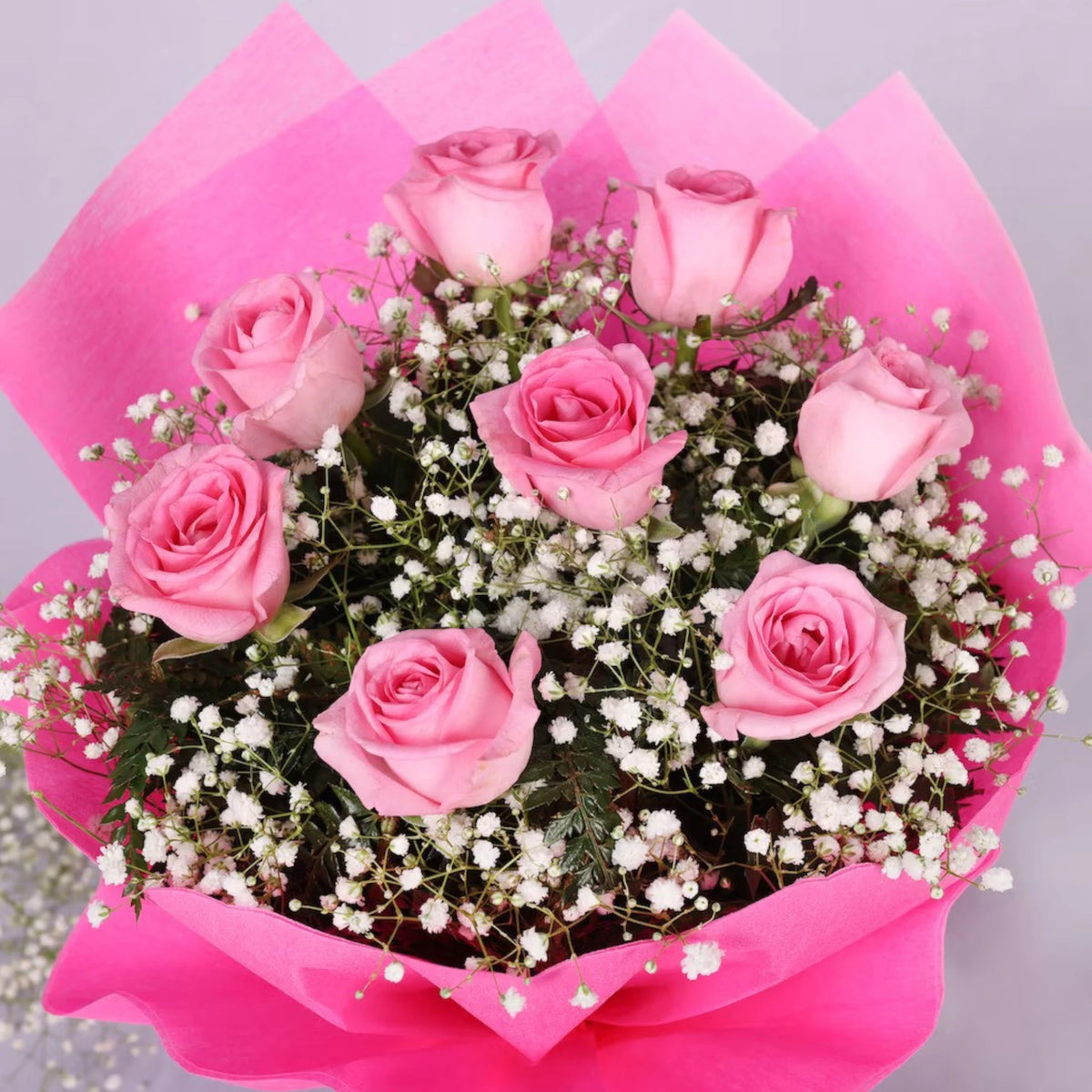 Exotic Pink Roses Bouquet featuring 8 pink roses with white baby's breath and green fillers, wrapped in pink paper. Express affection with this floral gift.