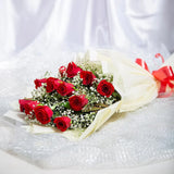 Classic Aura 12 Red Roses Bouquet - Perfect Gift laid flat, showcasing red roses with green and white fillers in soft cream wrapping and red ribbon.