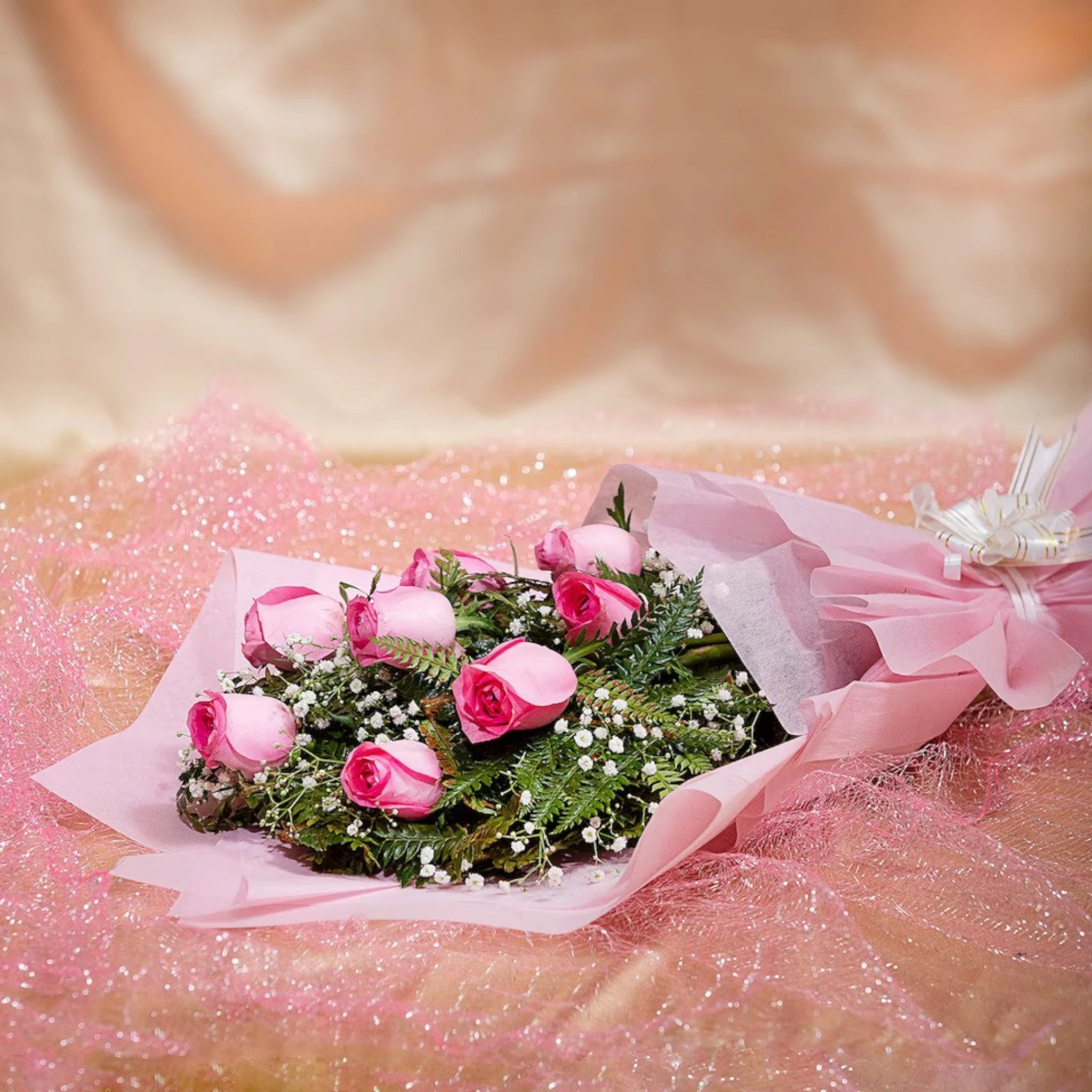 Elegant 8 Pink Roses Bouquet laid flat with greenery and white fillers, perfect for anniversaries or condolences. Shop same-day delivery gifts.