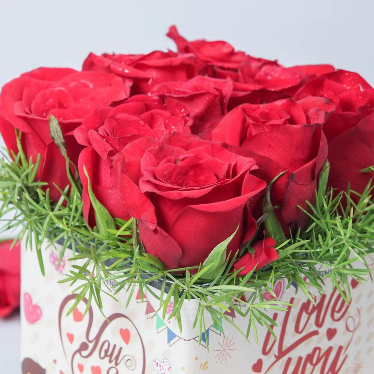 Close-up of Red Roses Sticker Vase - You And Me showing vibrant red roses with green fillers in a decorative glass vase, perfect for romantic gifting.