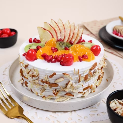 Fruit and Nut Cake topped with fresh apple slices, cherries, kiwi, orange segments, and pomegranate on vanilla sponge. Ideal for sweet cravings. Main image