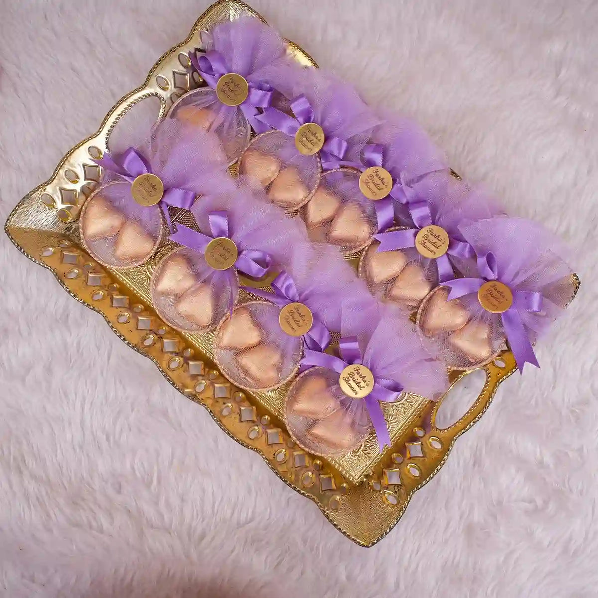 Heart Shower Favors with gold-wrapped chocolate hearts in lavender mesh pouches, tied with purple bows and personalized gold tags on a gold tray.
