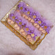 Heart Shower Favors with gold-wrapped chocolate hearts in lavender mesh pouches, tied with purple bows and personalized gold tags on a gold tray.