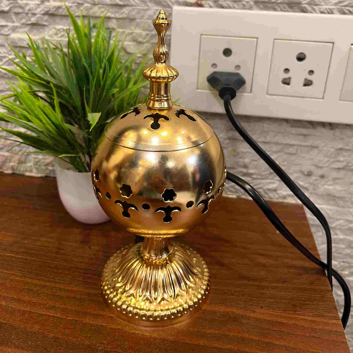 Electric Serene Essence Bakhoor Burner in gold finish placed on wooden surface, blends traditional elegance with modern functionality for home fragrance.