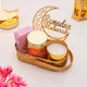 Decorative setup with candles, a 'Ramadan Mubarak' sign, and flowers on a light background