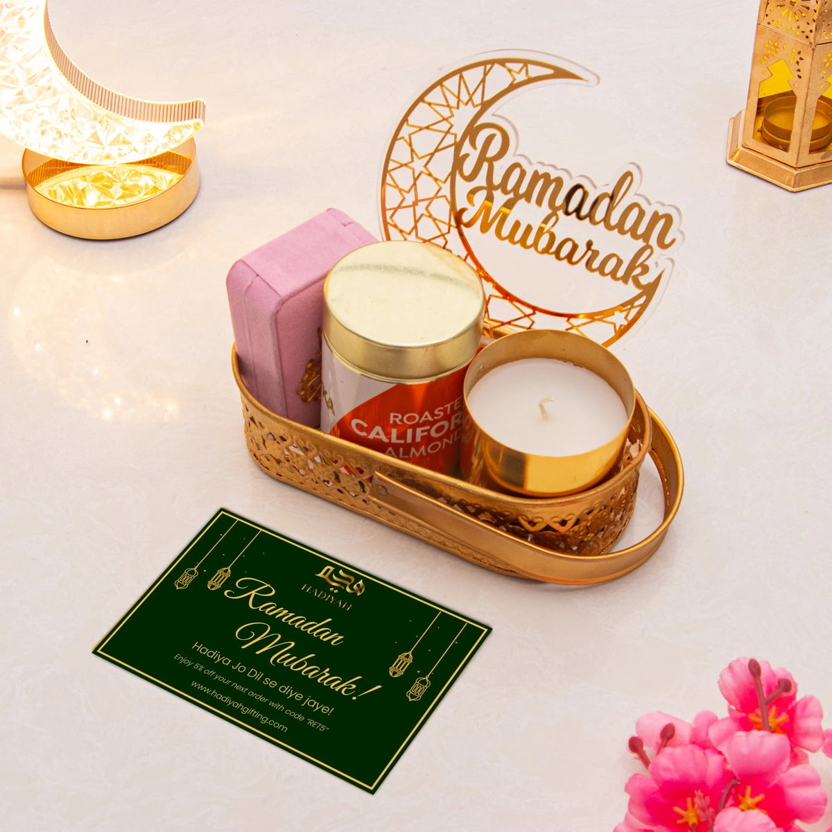 Luxe Ramadan Gift Hamper with pink tasbih box, almonds, candle, and Ramadan Mubarak greeting card in gold tray. Elegant Ramadan gift set.