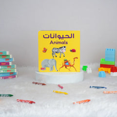 Children's book titled 'Animals' with colorful illustrations on a white surface with toys around.