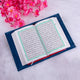 Open book with Arabic text on a white surface with pink flowers