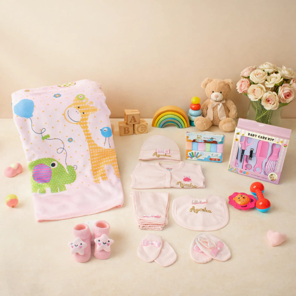 Baby Care Hamper - Baby Care kit with pink giraffe towel, embroidered babywear, grooming tools, and soft toys for newborn girls.
