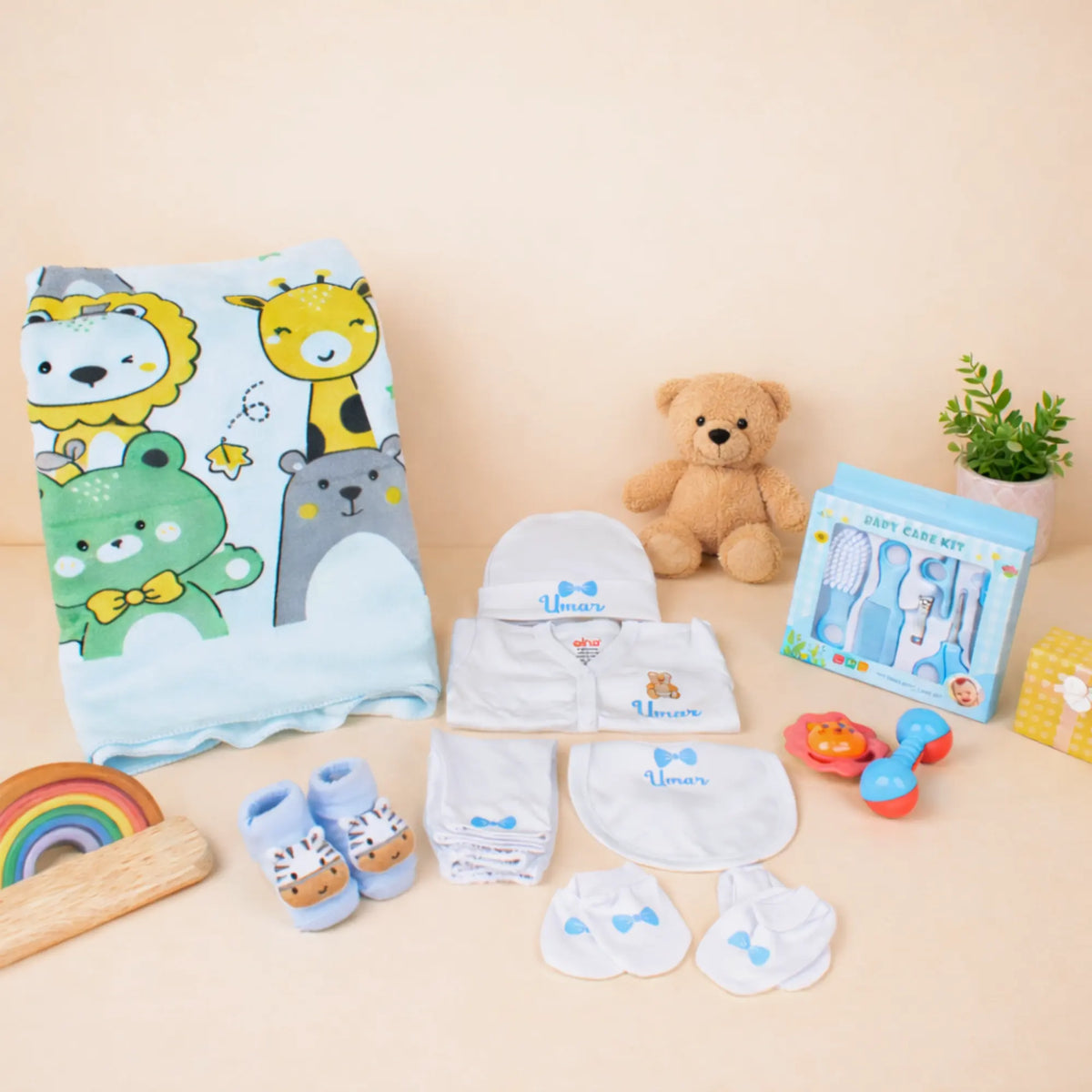 Baby Care Hamper - Baby Care set with blue animal print towel, grooming kit, personalized pyjama set, and soft toys for newborns.