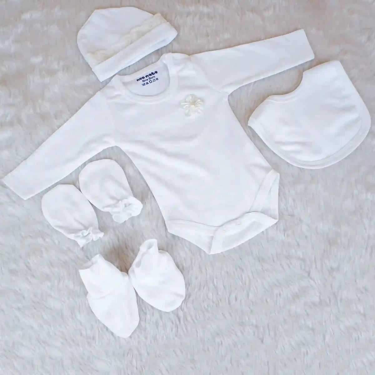 White baby outfit set with bodysuit, hat, bib, and booties on a light background