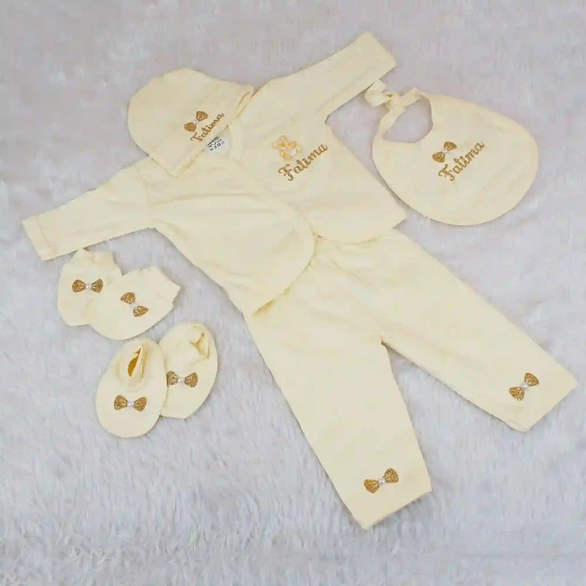 Yellow baby outfit set with matching accessories on a light gray background