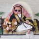 Infant dressed in Baby Boy Bisht Robes with keffiyeh and sunglasses, styled for Eid with plush camel toy and prayer rug.