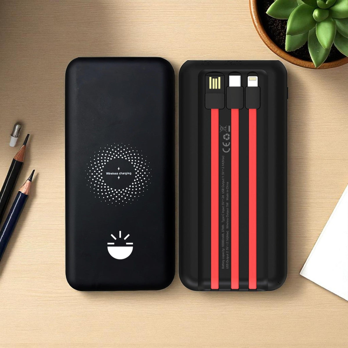 Black power bank with red cable heads on a wooden surface 