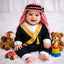 Baby boy in traditional attire with teddy bears and colorful stacking toys