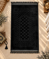 Black Janamaz with Name - Custom Black Prayer Rug laid out on marble floor, featuring intricate velvet texture and tassel edges, ideal for gifting.