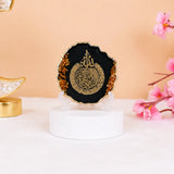Black 3" Ayatul Kursi Frame with golden flakes, perfect for Ramadan & EID decorations or gifting. Set on a white base with pink flowers nearby.