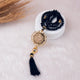 Black beaded necklace with gold accents and tassel on a white surface