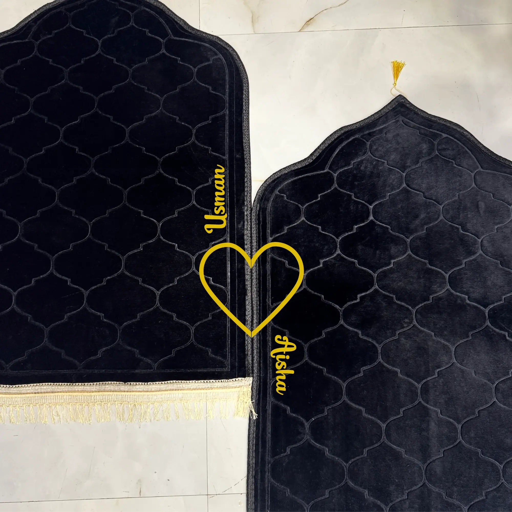 Two black prayer mats with gold embroidery on a marble floor. Main image