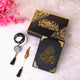 Black and gold decorative items with Arabic calligraphy on a white surface with pink flowers.