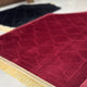 Angled view of maroon dome-shaped Janamaz from the Couple Janamaz Set, showcasing plush texture and elegant gold fringe detailing.