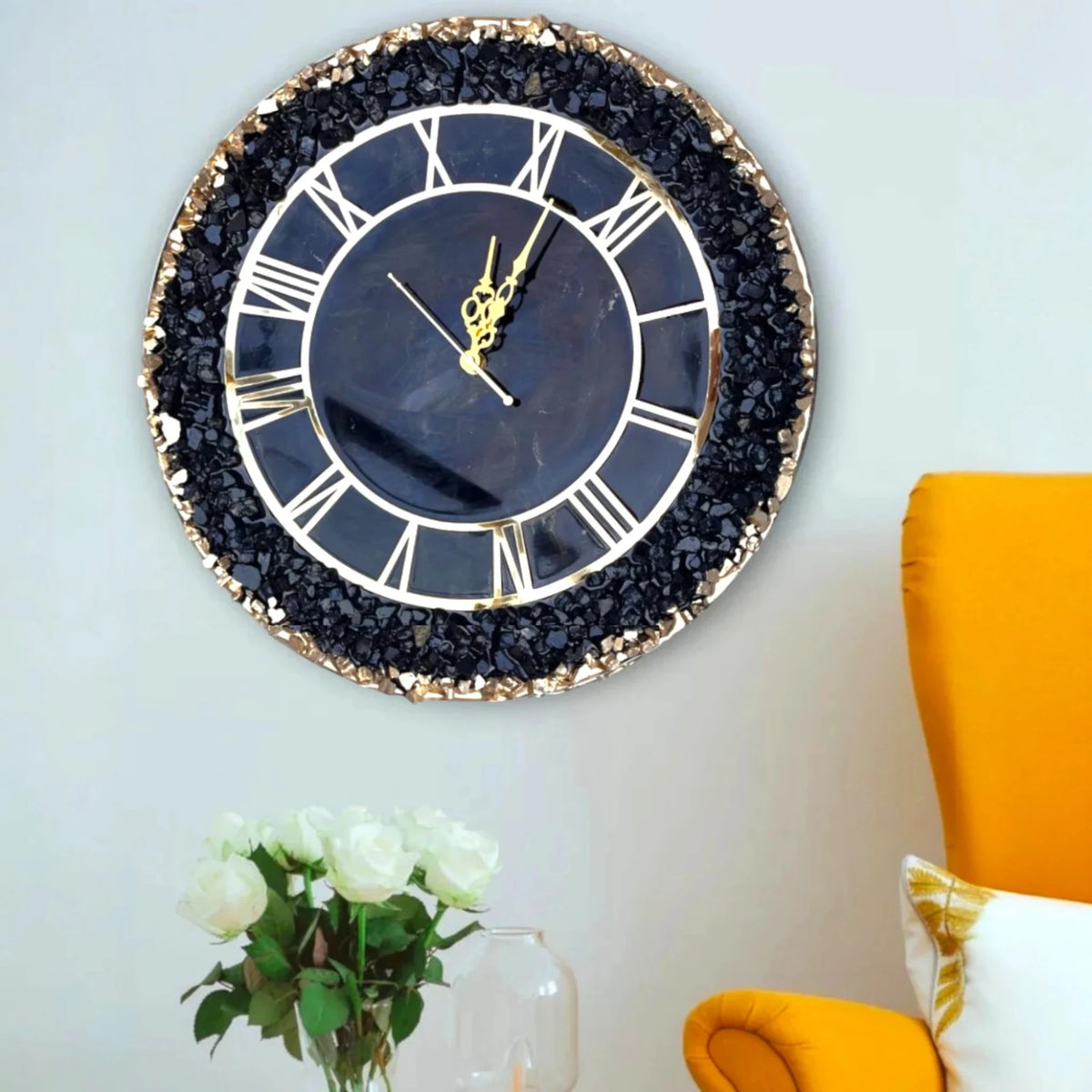 Black Grace Wall Clock with gold detailing and gemstone edge hung above a yellow chair. Stylish wall decor for contemporary homes.