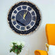 Black Grace Wall Clock with gold detailing and gemstone edge hung above a yellow chair. Stylish wall decor for contemporary homes.