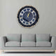 Black Grace Wall Clock with gold Roman numerals and crystal accents mounted above a grey sofa. Modern decor for luxury living rooms.