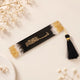 Decorative black bookmark with tassel on a fluffy white surface with pink flowers.