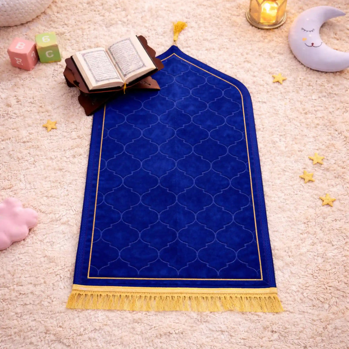 Close-up of prayer rug with Quran and moon-shaped lamp