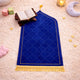 Close-up of prayer rug with Quran and moon-shaped lamp