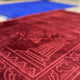 Close-up of premium maroon Janamaz from the Blue & Maroon Janamaz Set, showcasing intricate embossed design and soft texture.