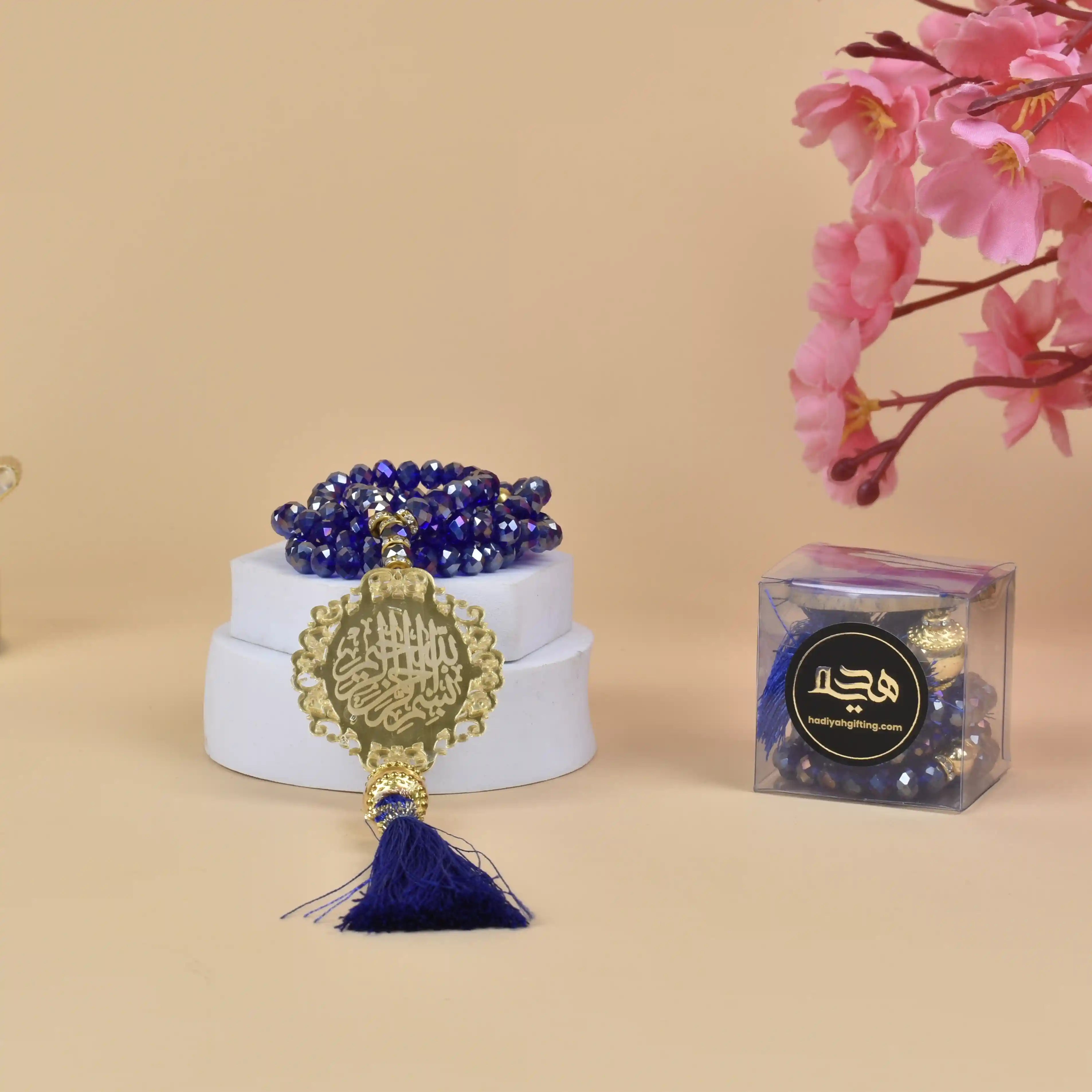 Blue Crystal Tasbeeh with 100 beads and Bismillah charm, ideal Islamic gift for Hajj, Umrah, or weddings. Displayed with gift box and floral decor. Main image