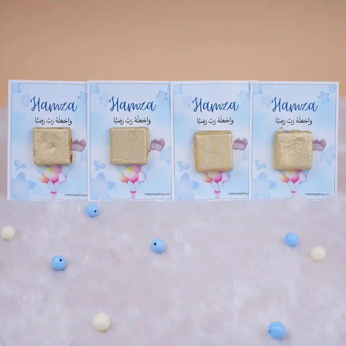 Row of Aqiqah Sweet Blessings Favors with gold-wrapped chocolates on blue personalized cards, great for Aqiqah event giveaways.