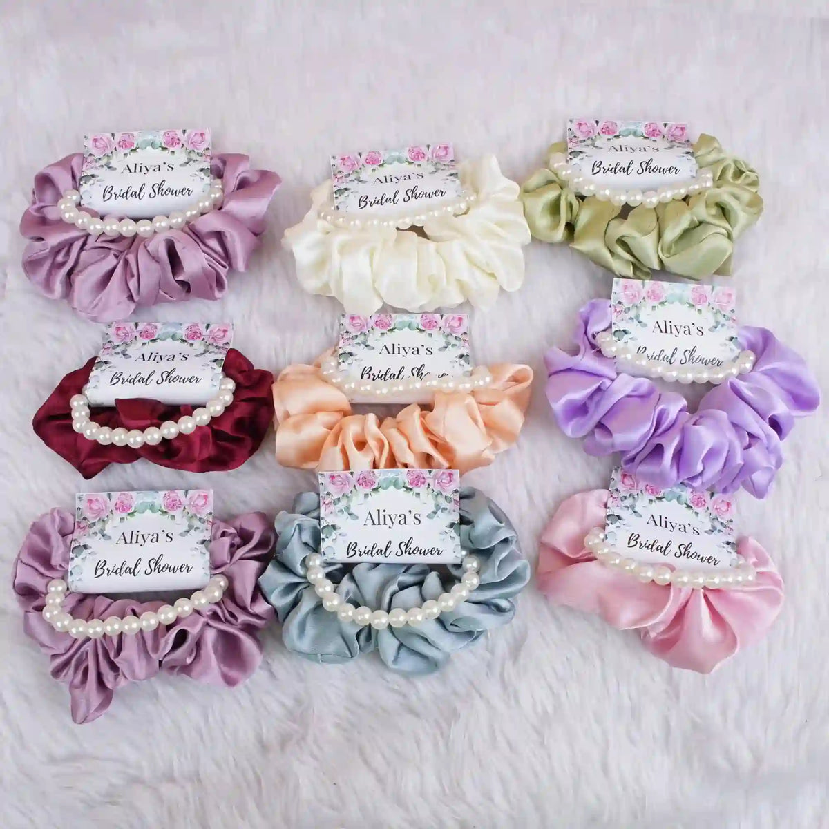 Set of colorful hair scrunchies with personalized labels on a soft surface