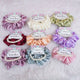 Set of colorful hair scrunchies with personalized labels on a soft surface