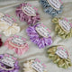 Set of colorful scrunchies with floral labels on a light fabric background