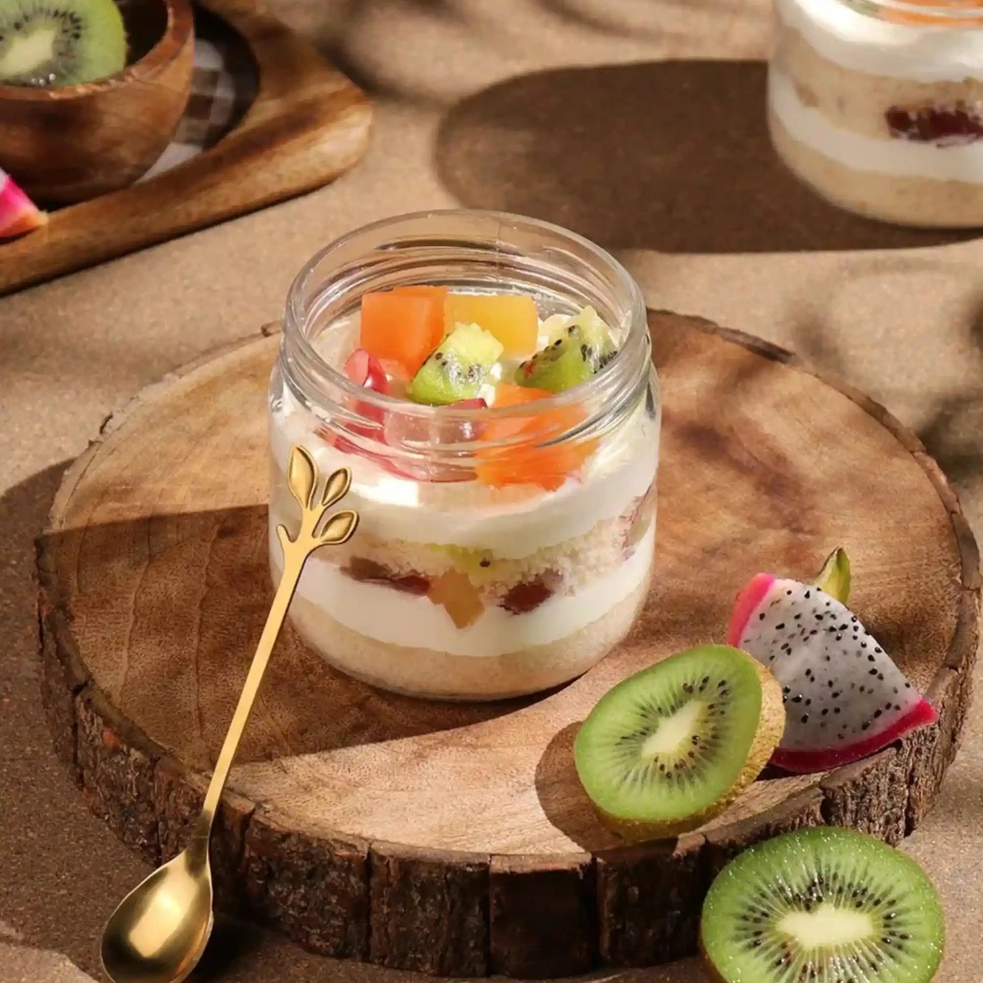Fruit parfait in a jar on a wooden board with kiwi and dragon fruit slices. Main image