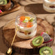 Fruit parfait in a jar on a wooden board with kiwi and dragon fruit slices.