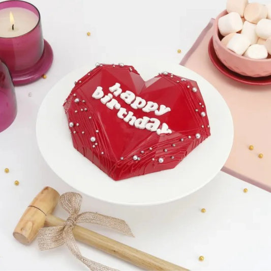 Heart-shaped Red Velvet Pinata Cake on white stand, perfect for birthdays with hidden candy surprise inside and elegant decoration.