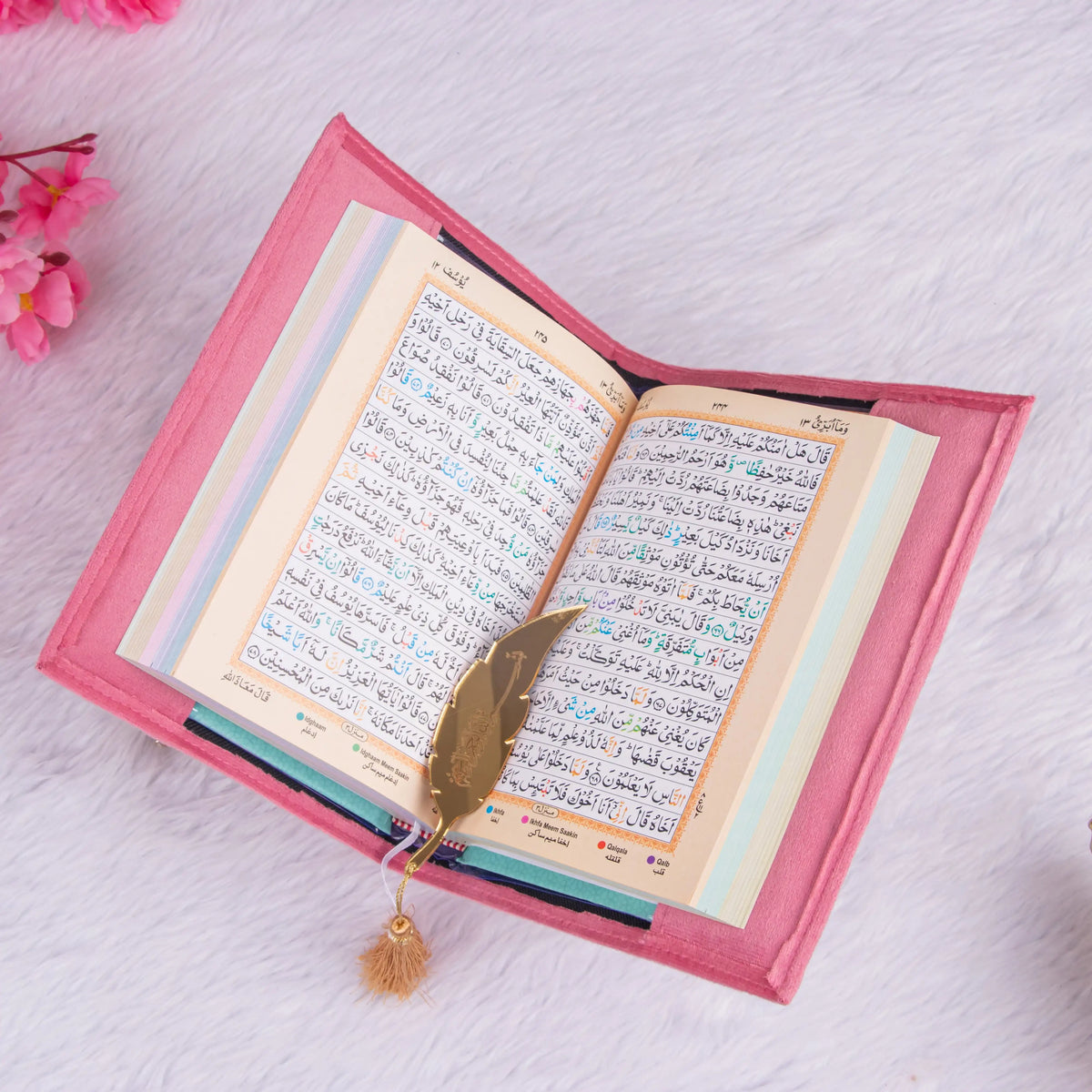 Open Quran with pink velvet cover and golden feather bookmark, included in the Sawab-e-Jariya bridal gift hamper. Elegant religious gift.